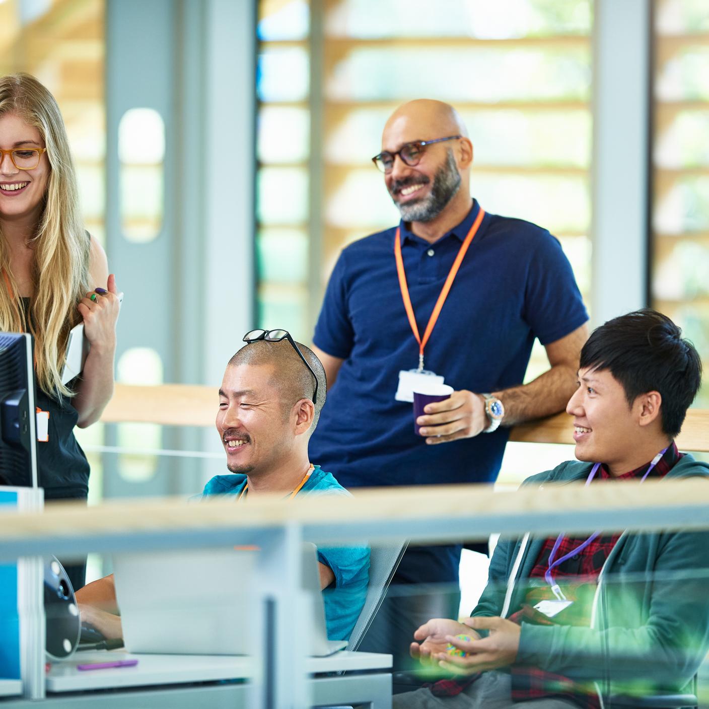 A Guide To Enhancing Social Value In Your Organization - Men and woman smiling and talking at desk in modern tech company