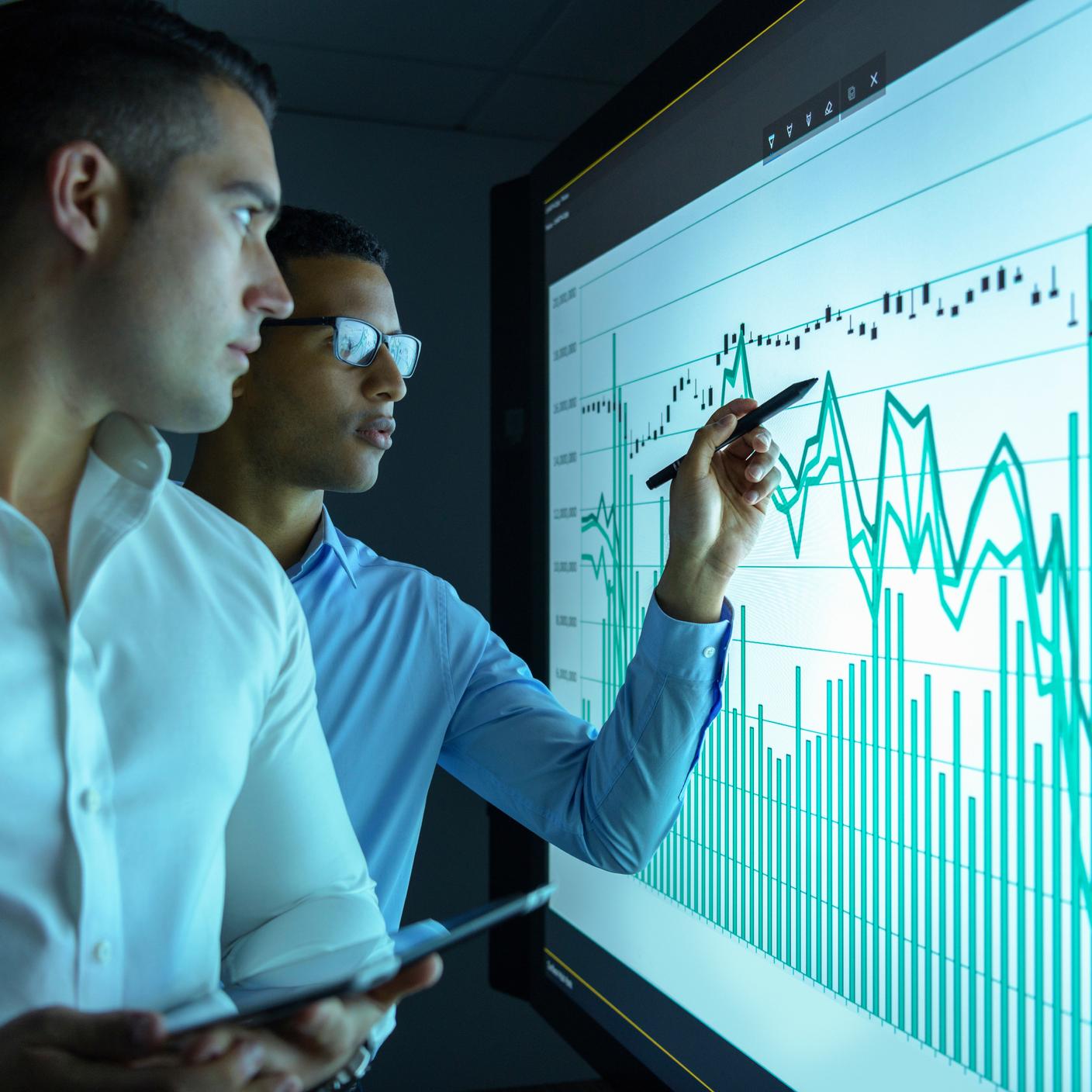 Businessmen studying graphs on an interactive screen