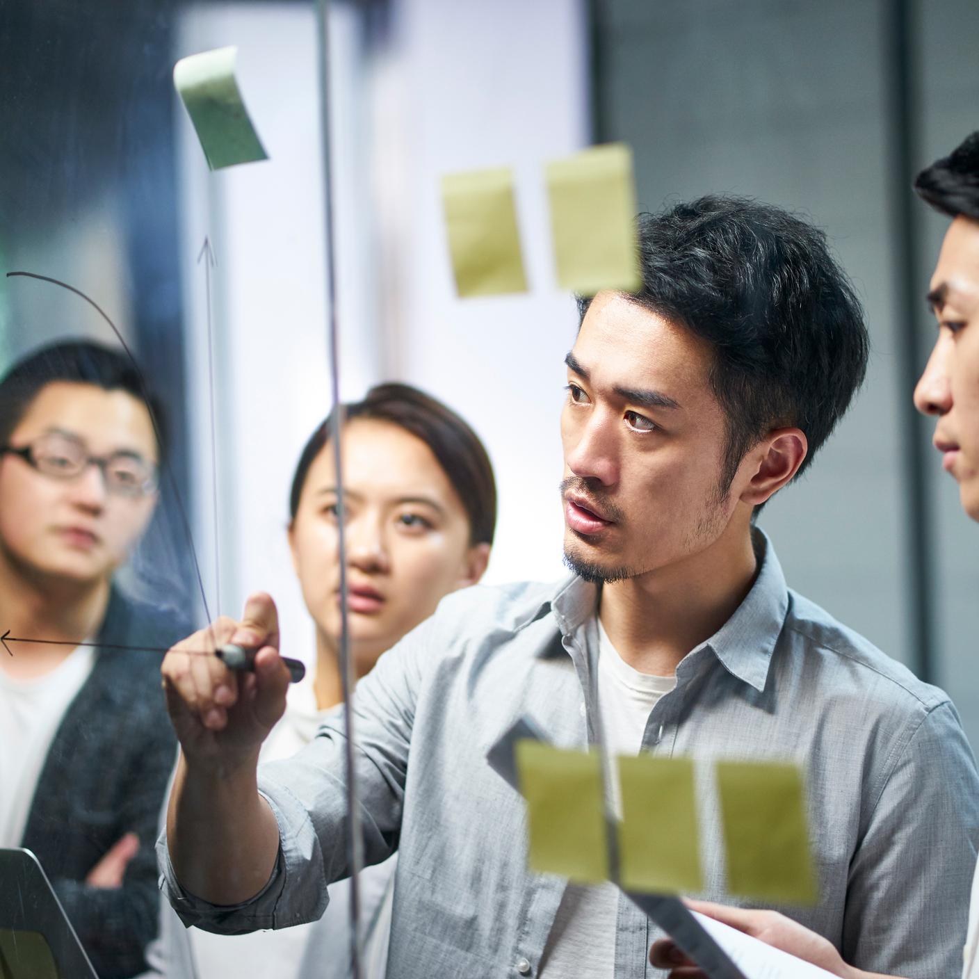 workshop in office with post-its on glass wall formulating business strategies