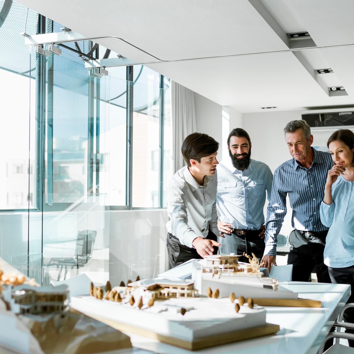 Team of architects examining model in board room