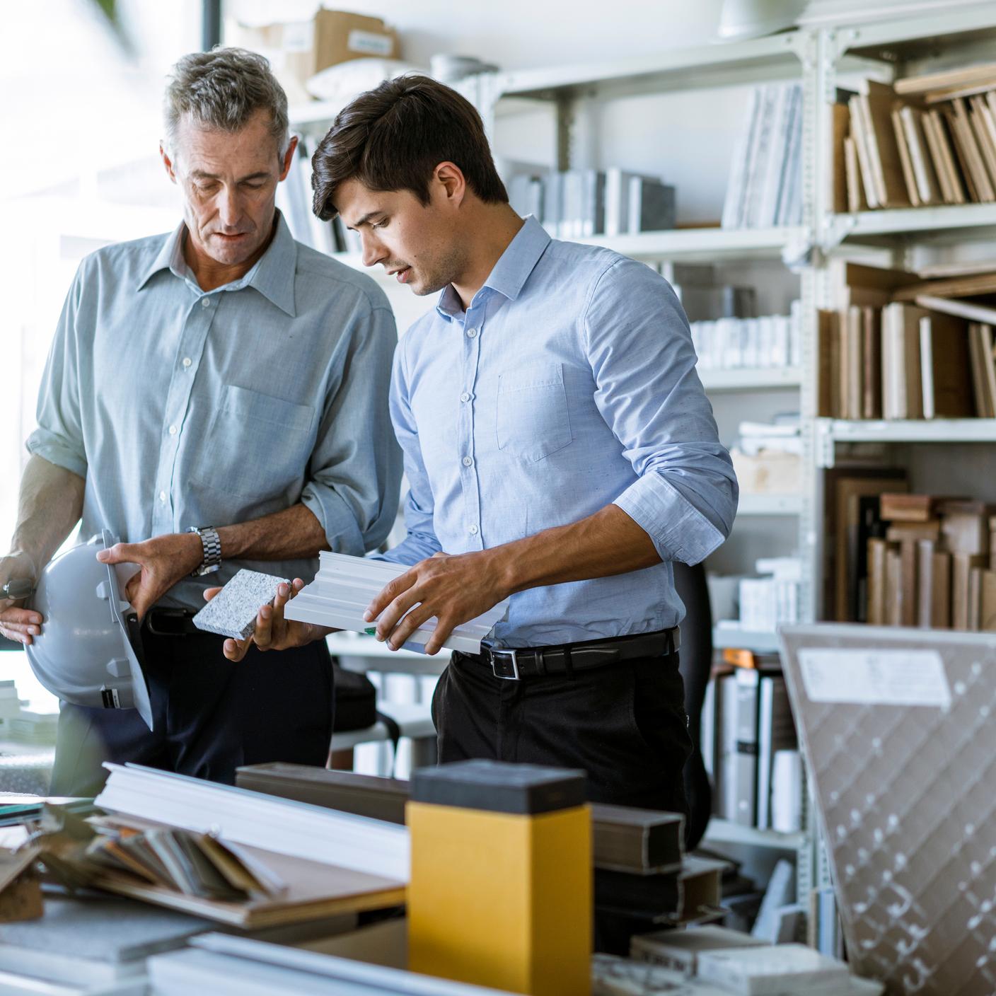 Buildings and construction - Male architects holding construction equipment at desk in office