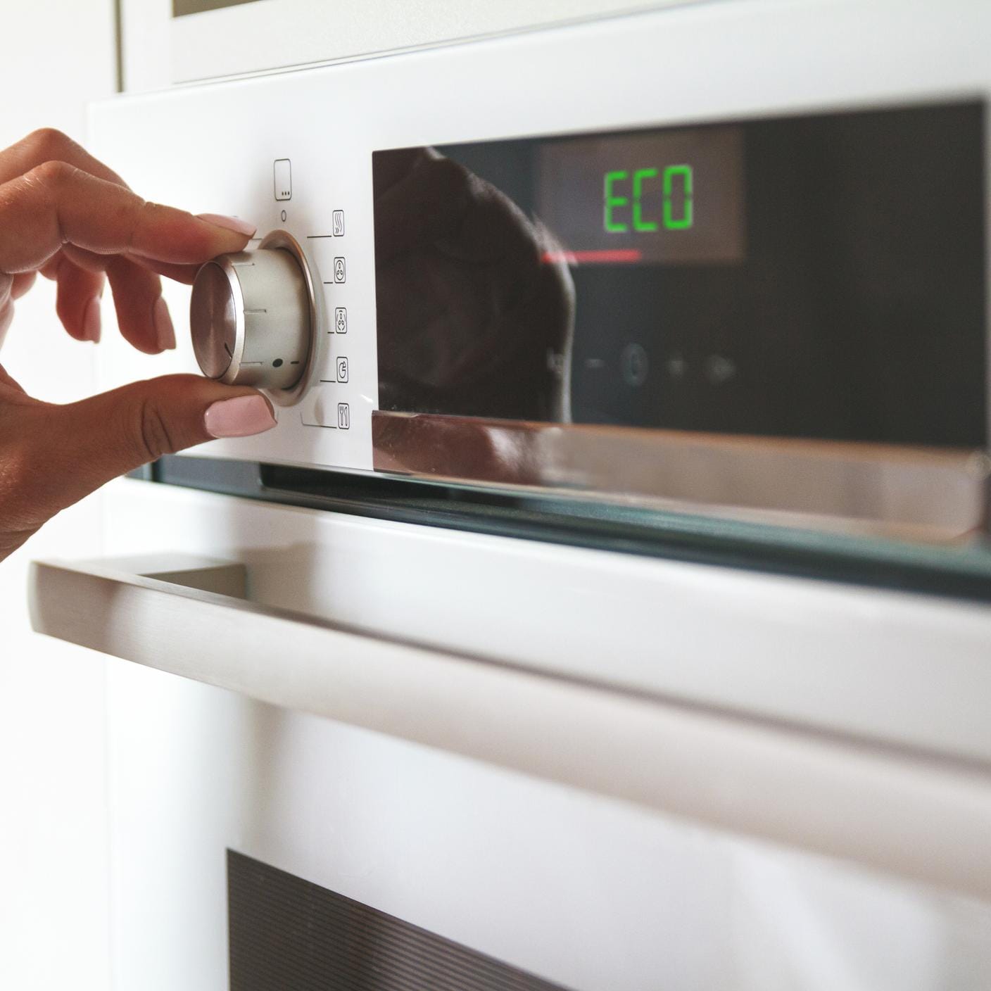 Person selecting eco mode operation of an electric oven
