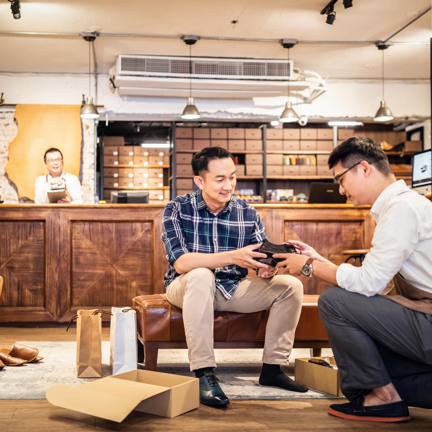 Salesman introducing new shoes to customer in a shoe store.