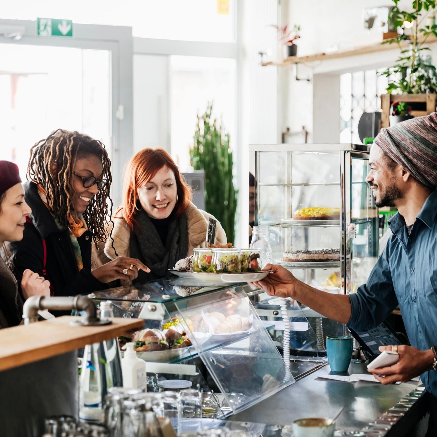 Food safety - A waiter serving three women ordering at a vegan cafe counter