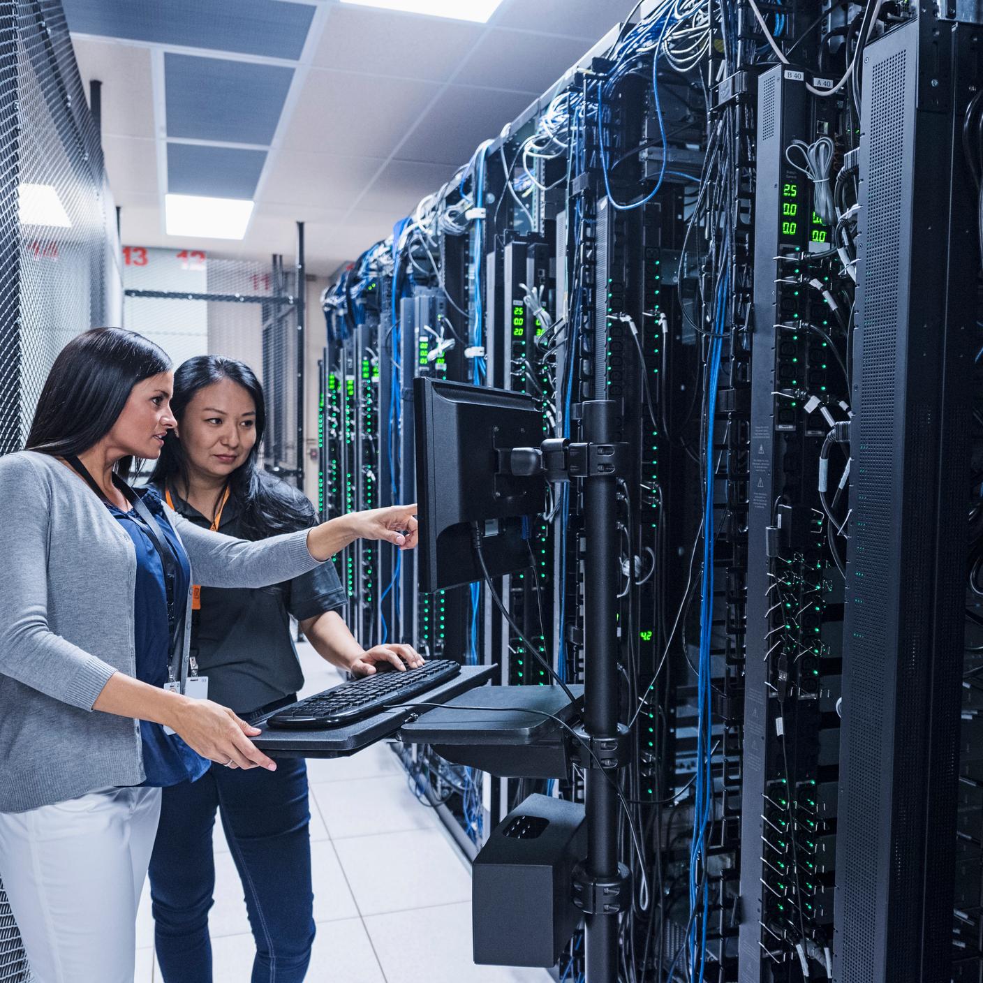 Two coworkers working with computer in server room