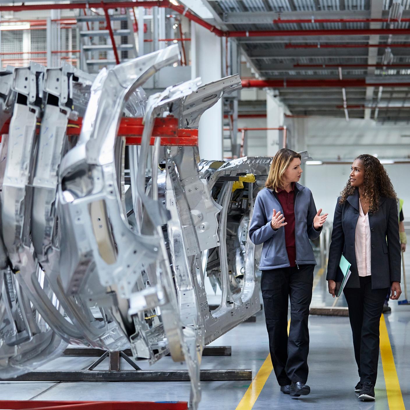 Automotive - Female engineers discussing by car chassis