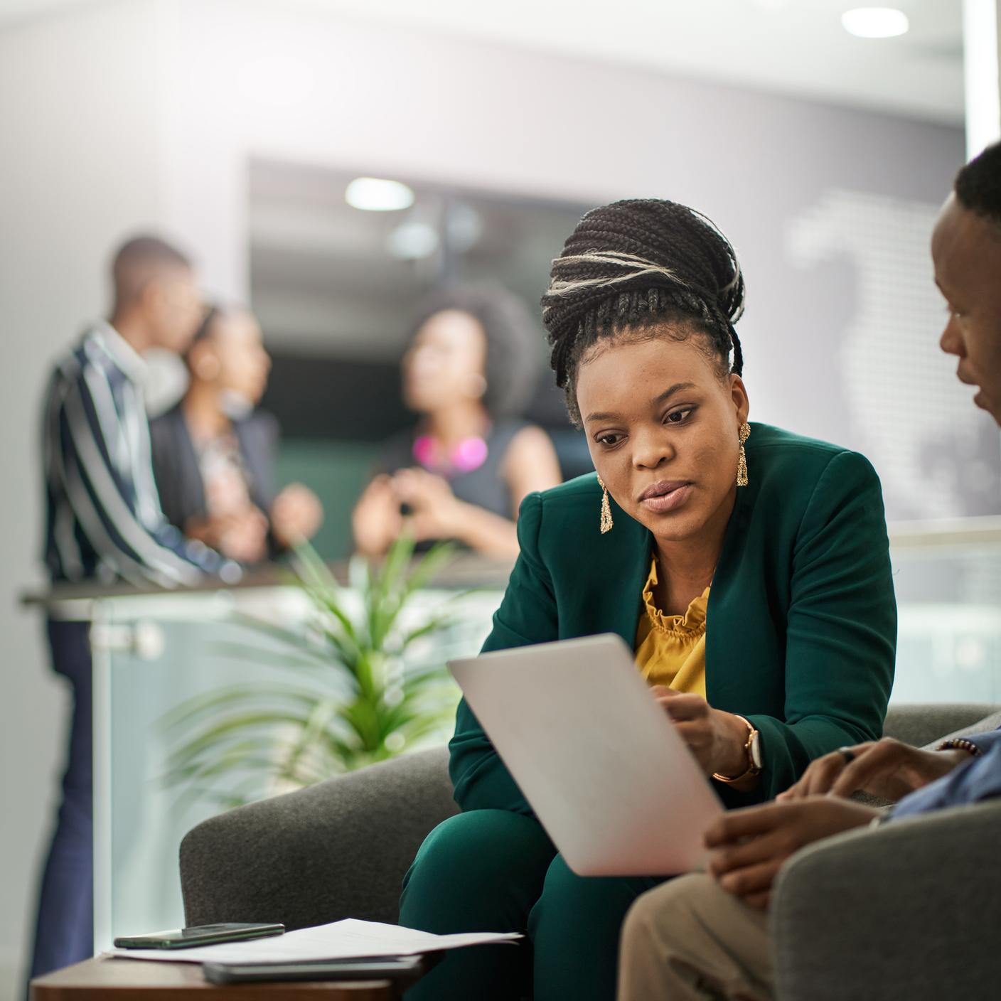 African businesspeople brainstorming in office lobby.