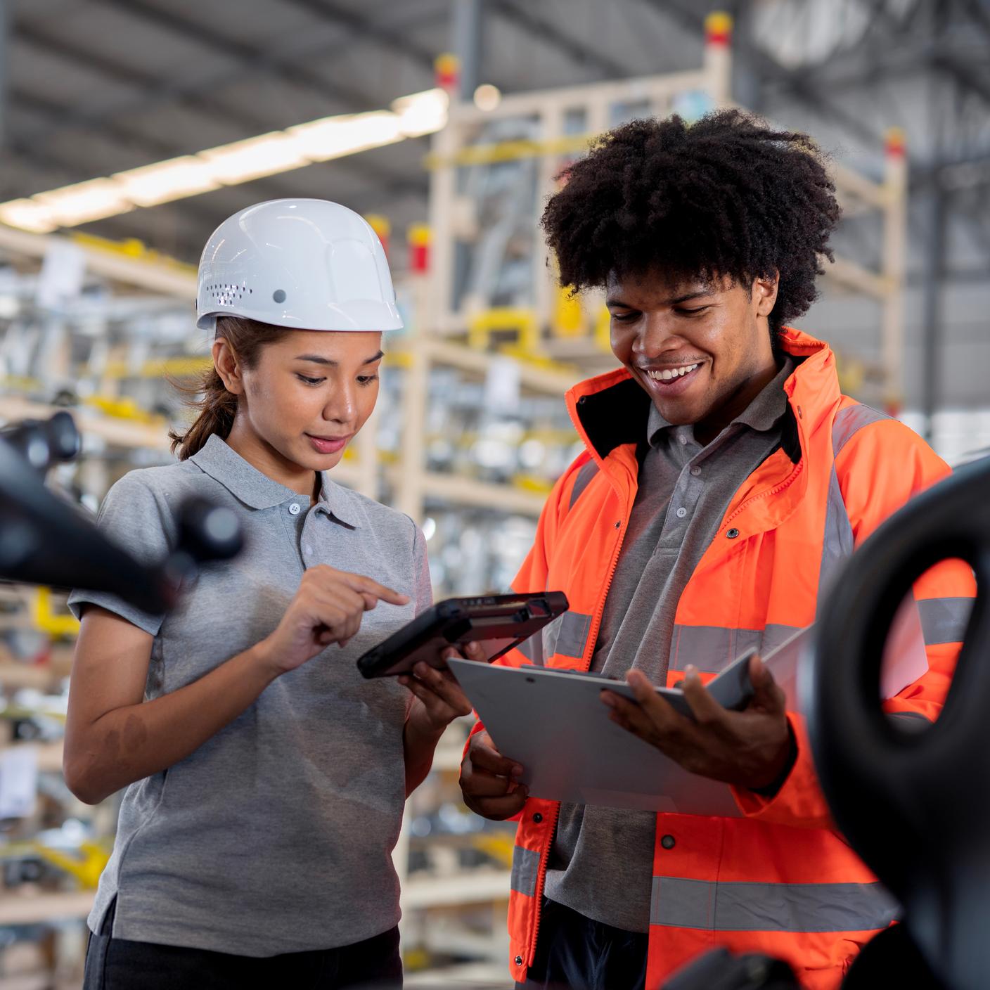 Quality Management - Warehouse Supervisor discussing a tablet computer with warehouse workers