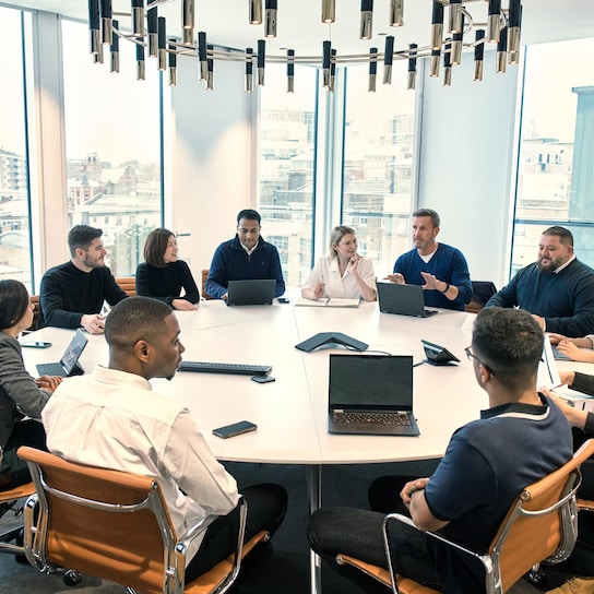 Large meeting of people around a circular meeting table