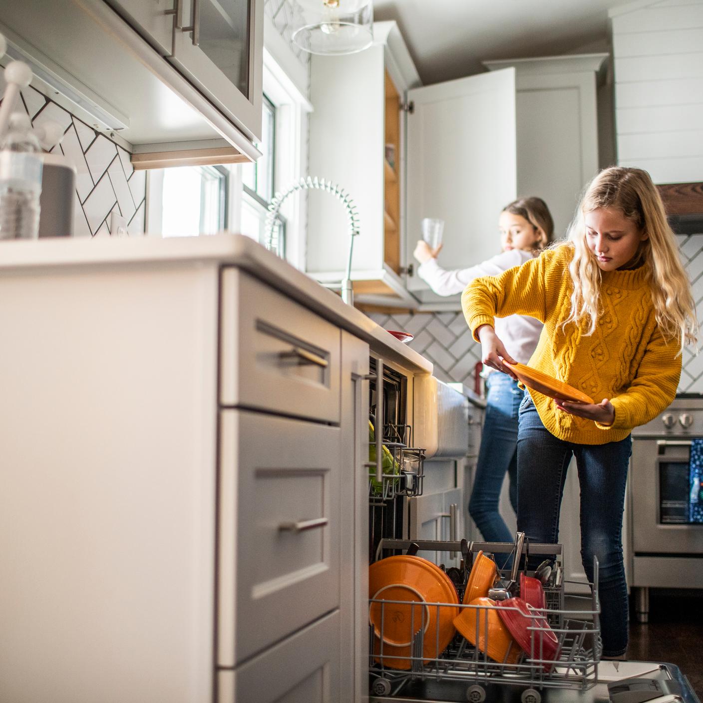 Supporting move to low energy system -  Tween girls doing dishes in kitchen