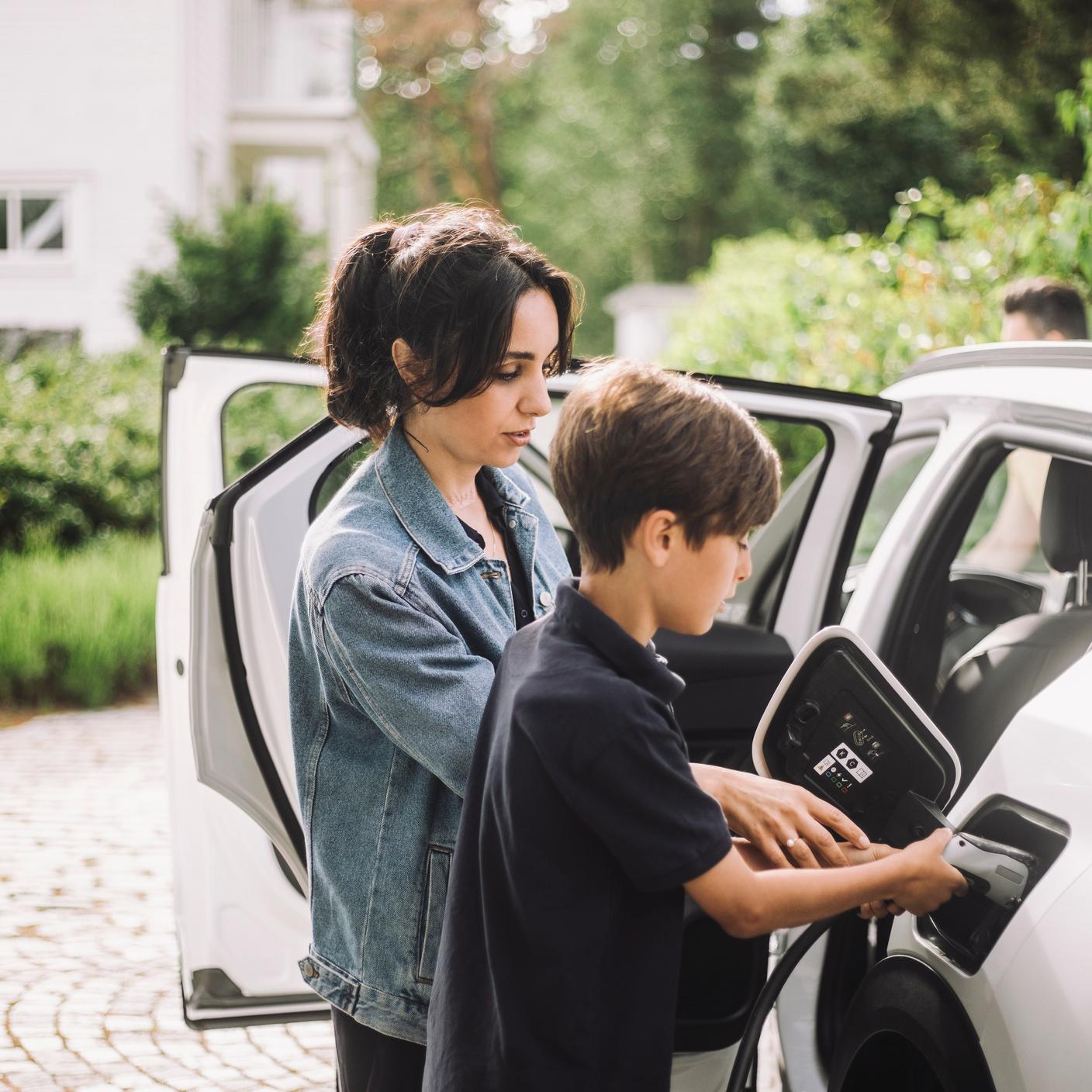 Mother and son plugging in Electric Vehicle