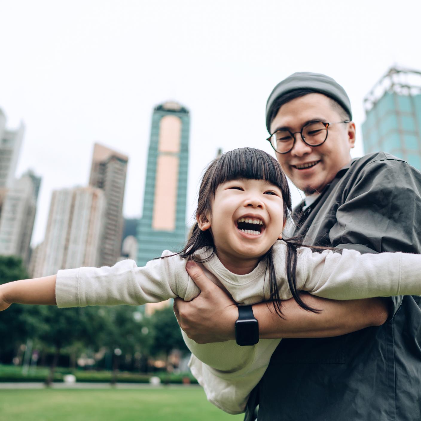 Girl having fun with her father outdoors in urban park. 
