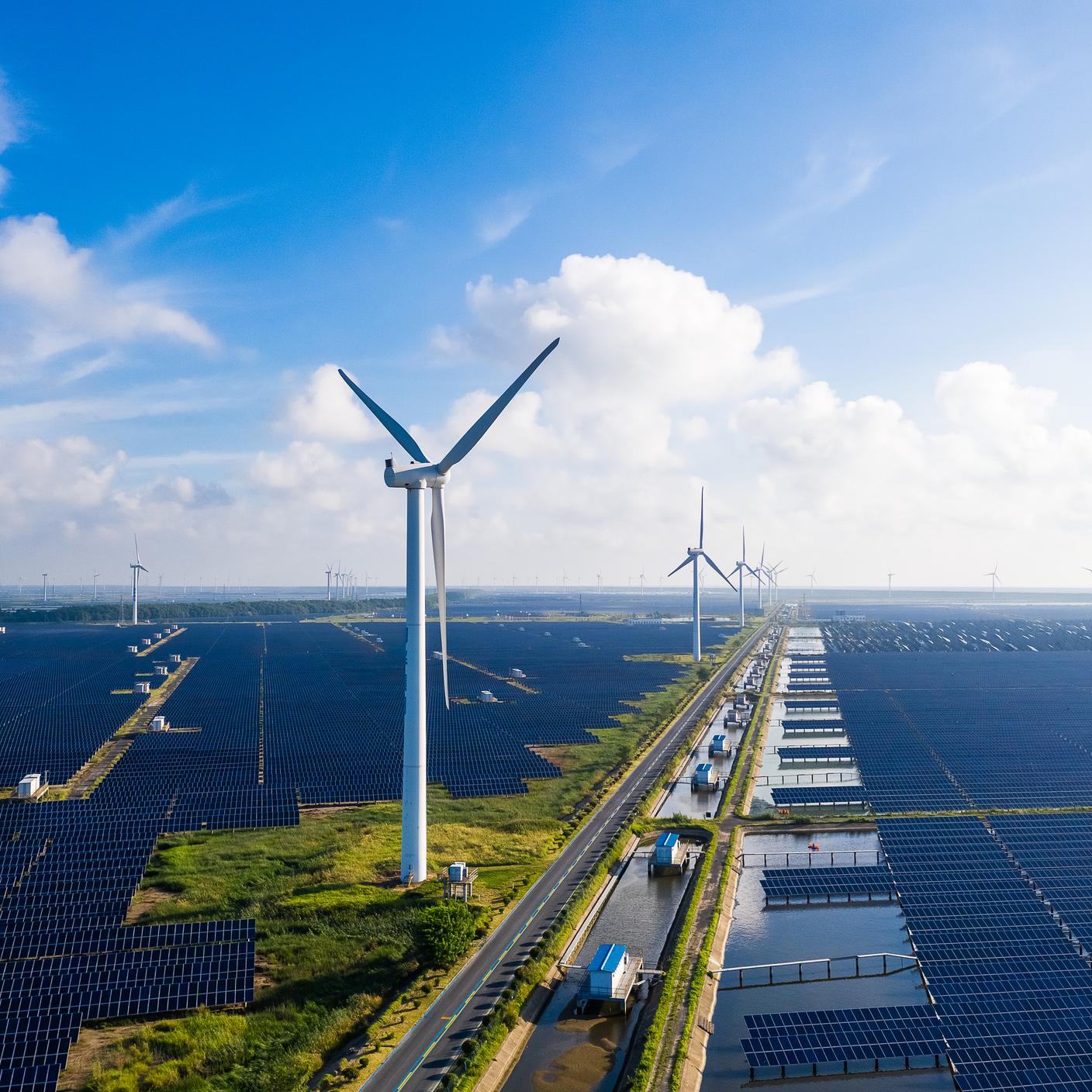 Solar power stations in plain areas, wind turbines in the distance. Yancheng City, Jiangsu Province, China.