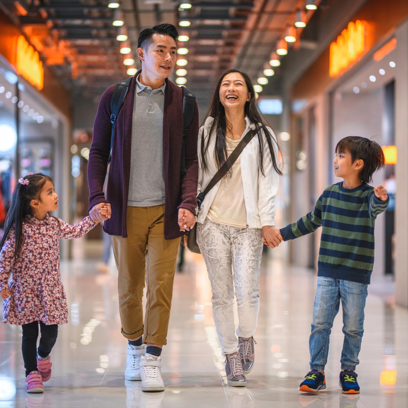 Family holding hands as they walk and shop at shopping center