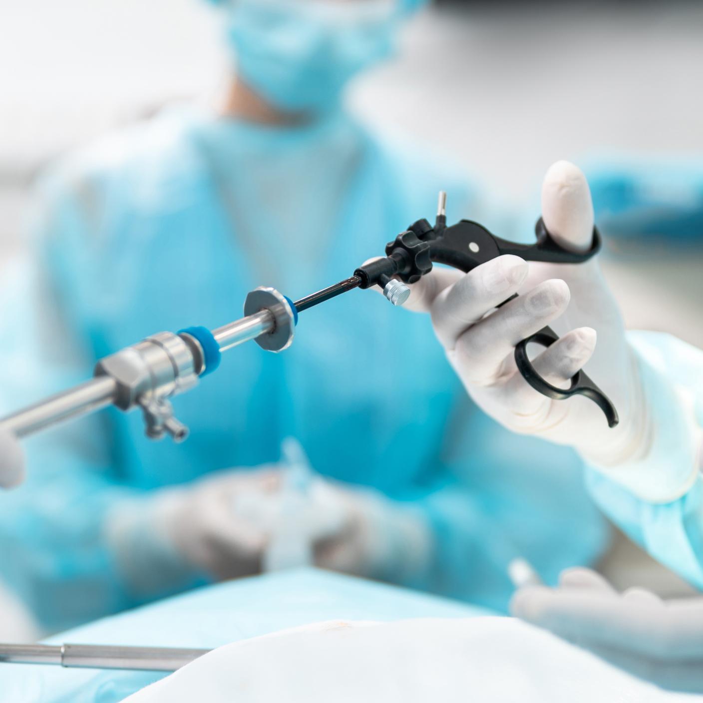 Close up of male and female hands holding laparoscopic grasper with trocar. 