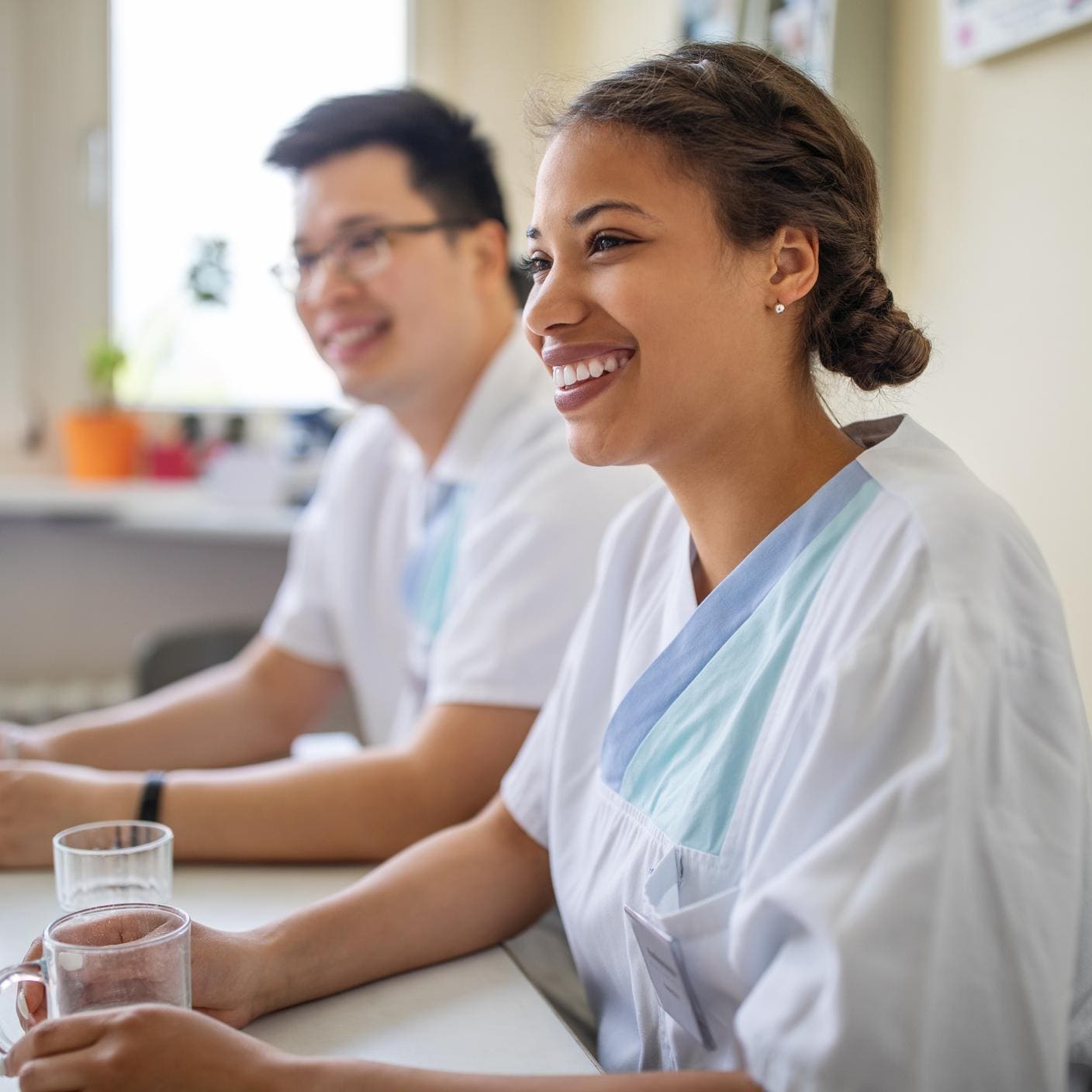 African female nurse sitting with coworkers in hospital during break