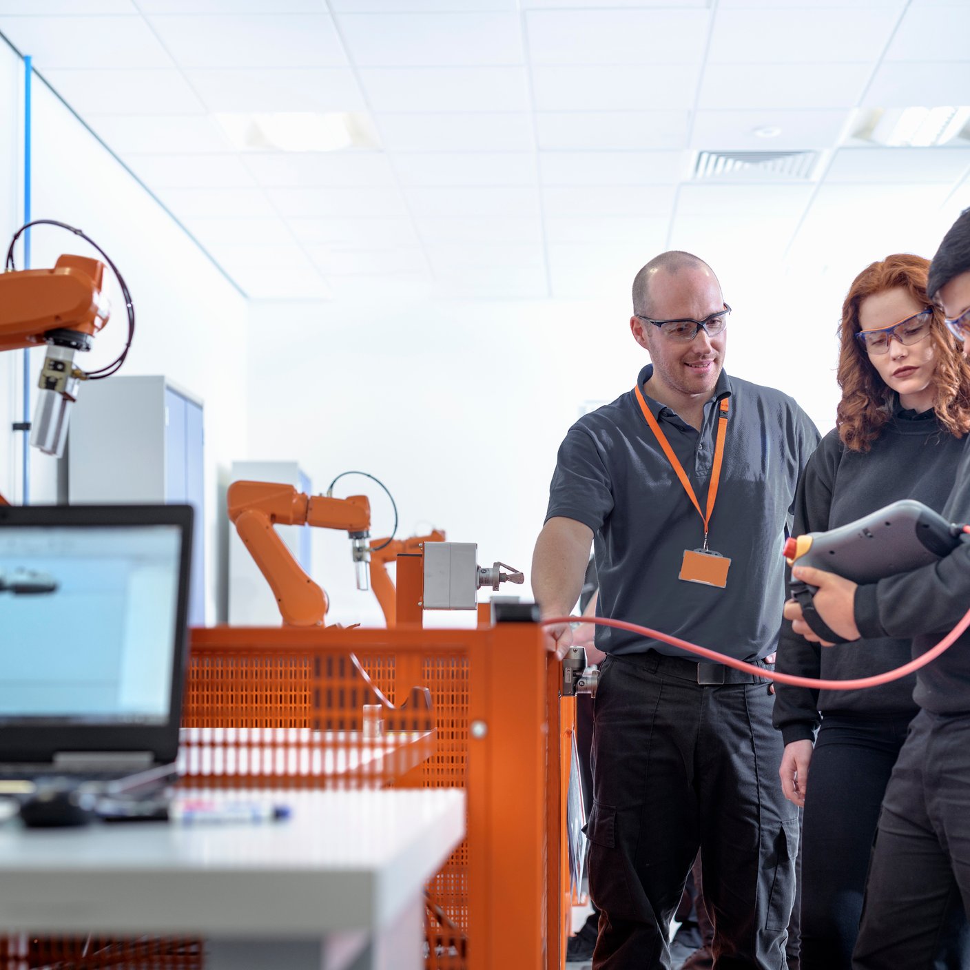 Robotics apprentices using test industrial robots in robotics facility