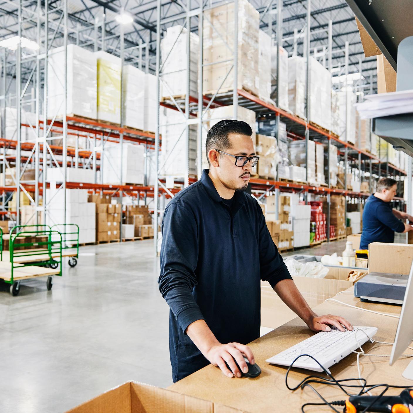 Supply Chain in Manufacturing - Male warehouse worker checking orders at computer workstation