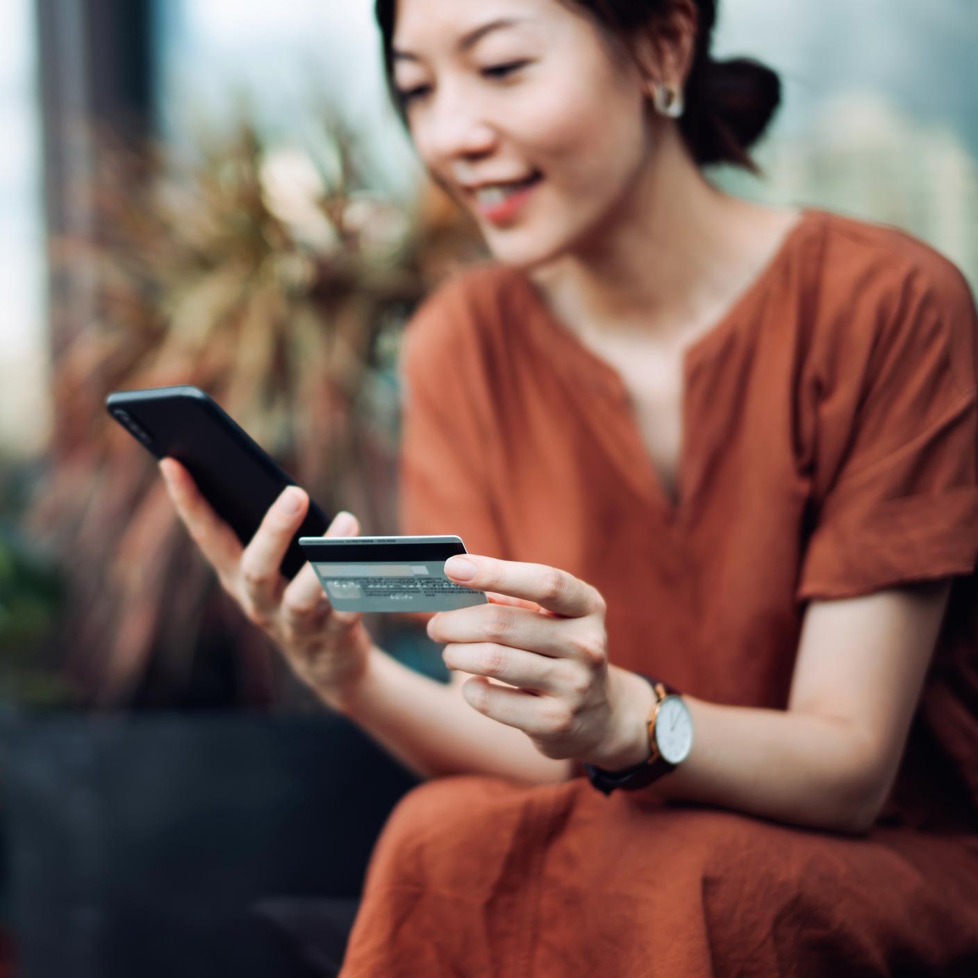 smiling young Asian woman relaxing on deck chair in the backyard