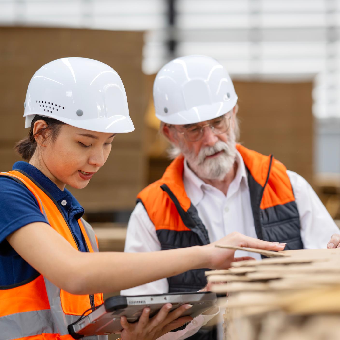 Raw Material Management and Quality Assurance Before Starting the Production Process. A female quality control engineer and senior male manager examine the quality of raw corrugated material based on quality standards in a factory warehouse.