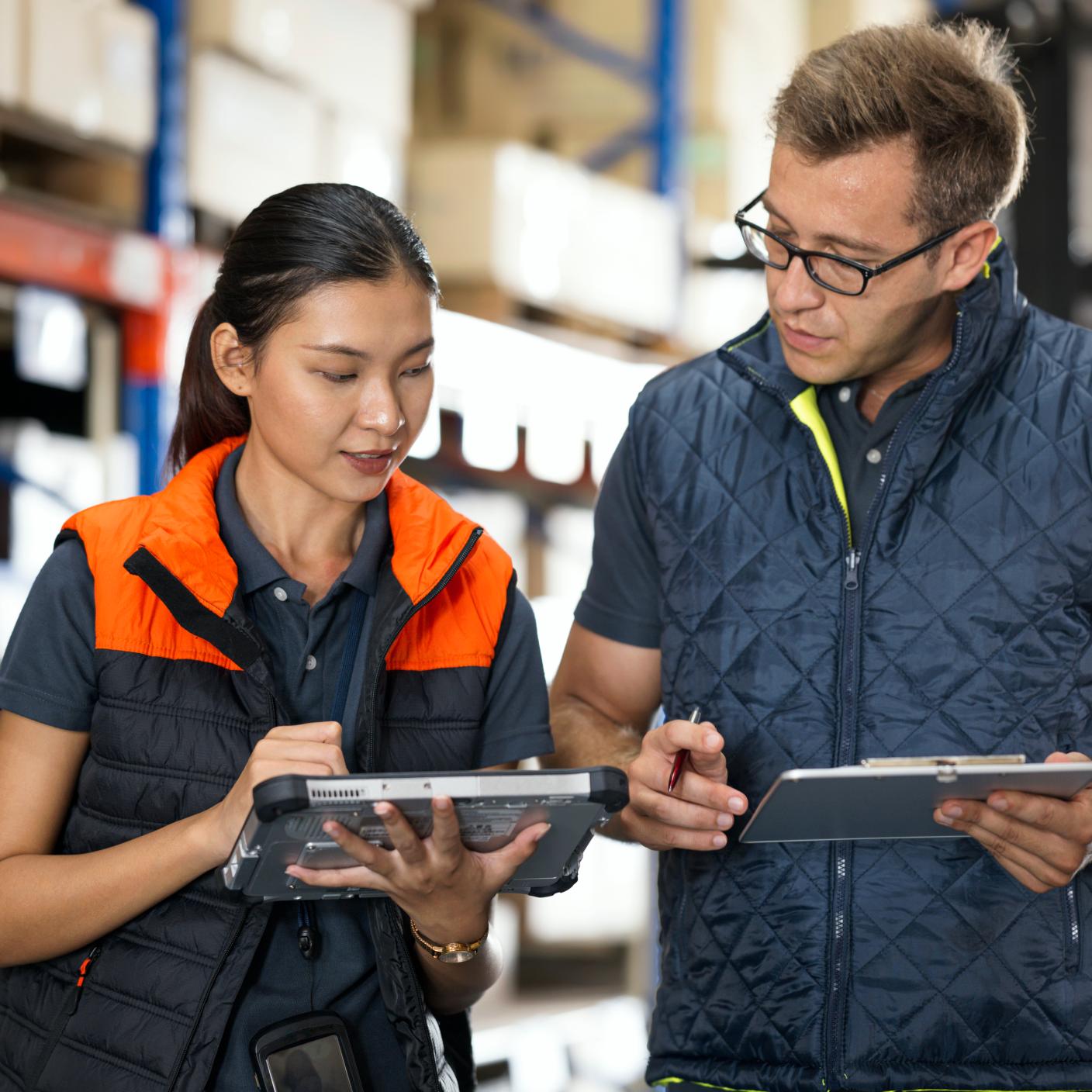 Using Cloud based Software as a Service (SaaS) for Warehouse Management System. Warehouse Management team discussing on customer shipment orders by software management in a factory warehouse.