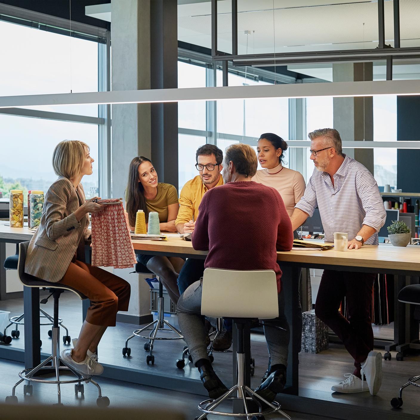 Business people discussing over fabric at conference table
