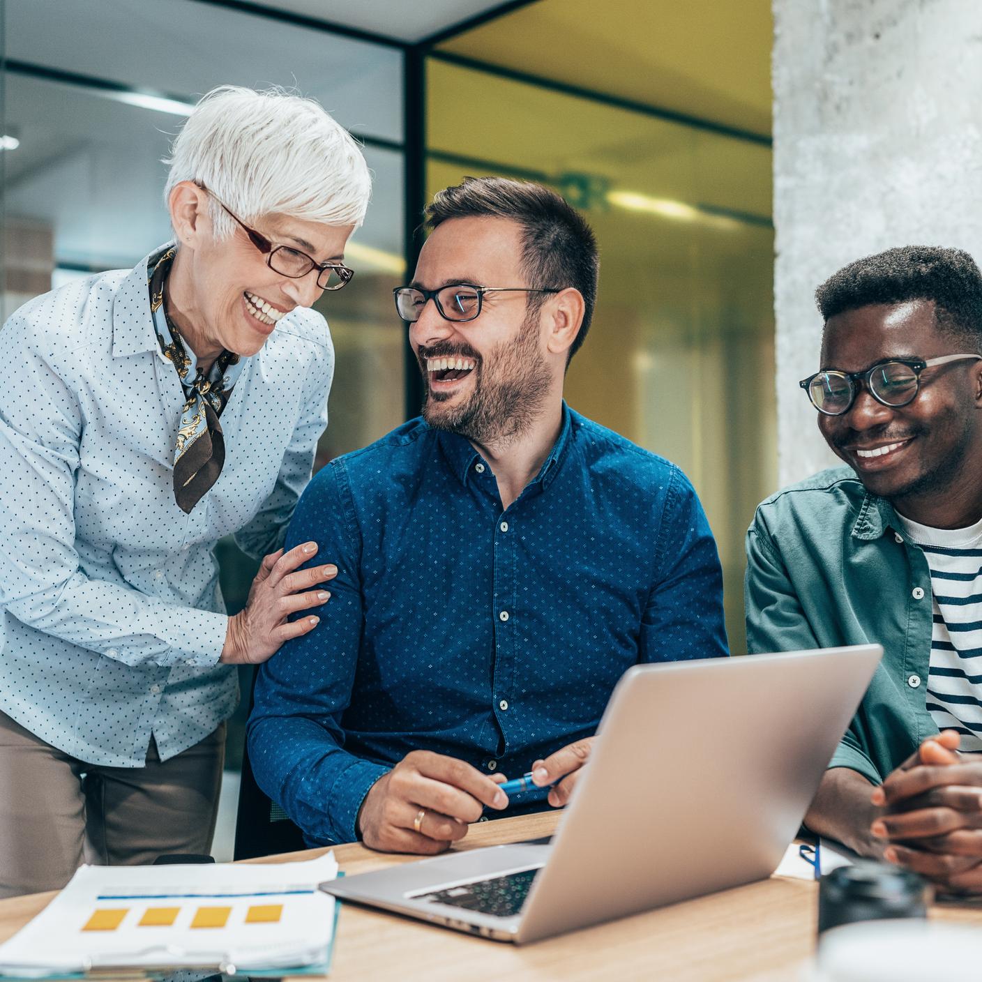 Drei multiethnische Geschäftsleute, die in einem modernen Büro diskutieren und lachen