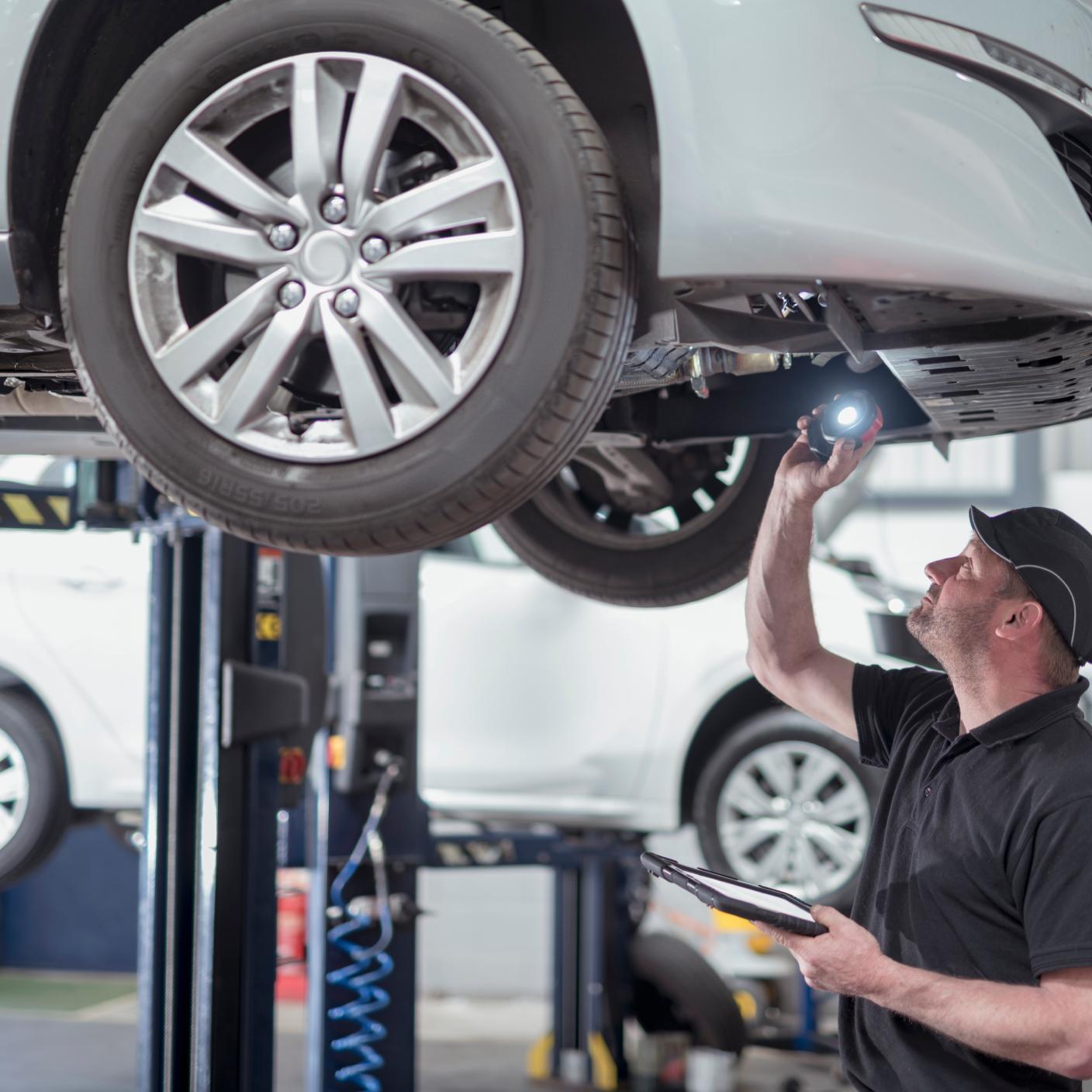 Engineer checking car on ramp in car service centre