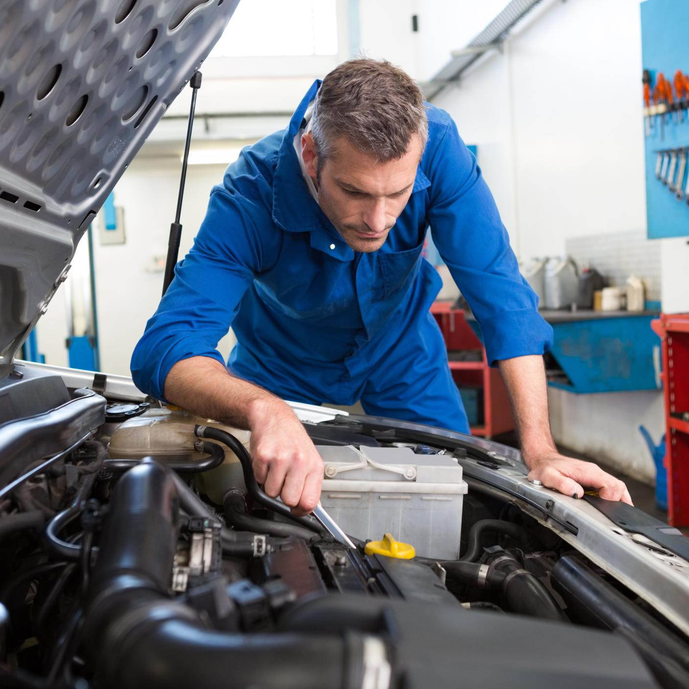 Mechanic examining under hood of car at the repair garage