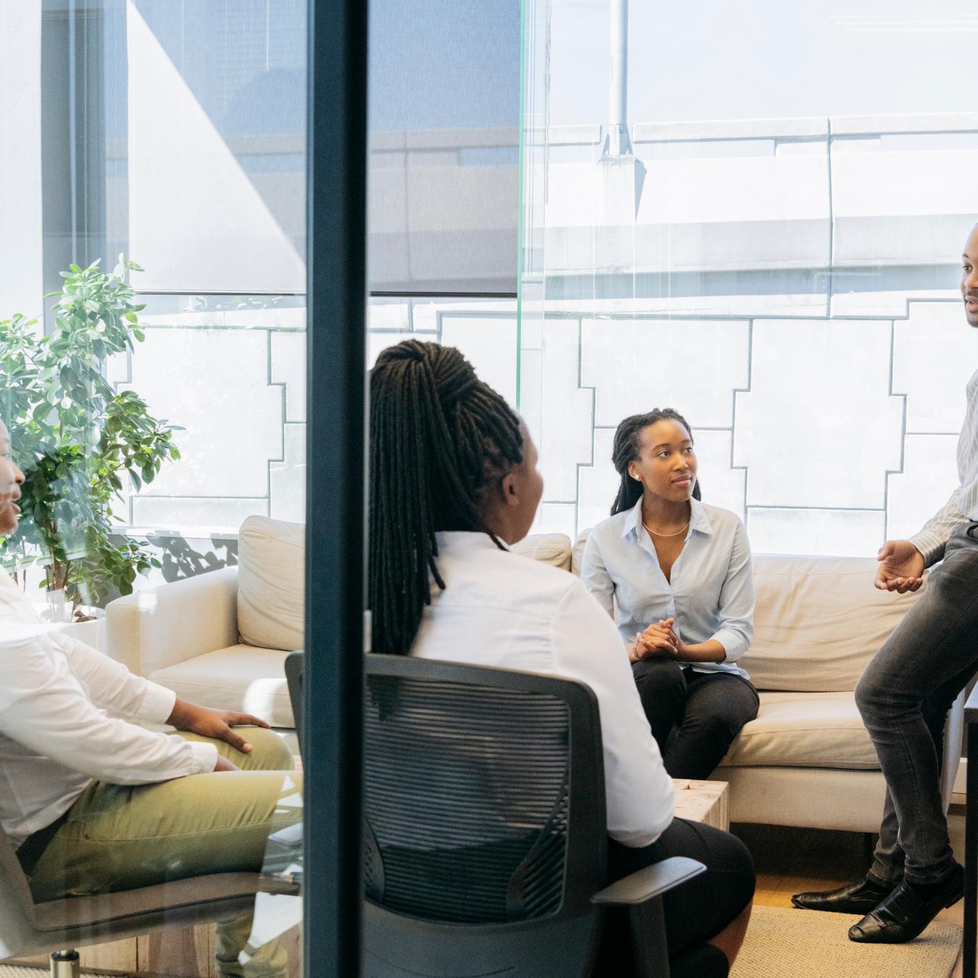 Group of African office workers in modern meeting room, young man gesturing and explaining, co-workers listening