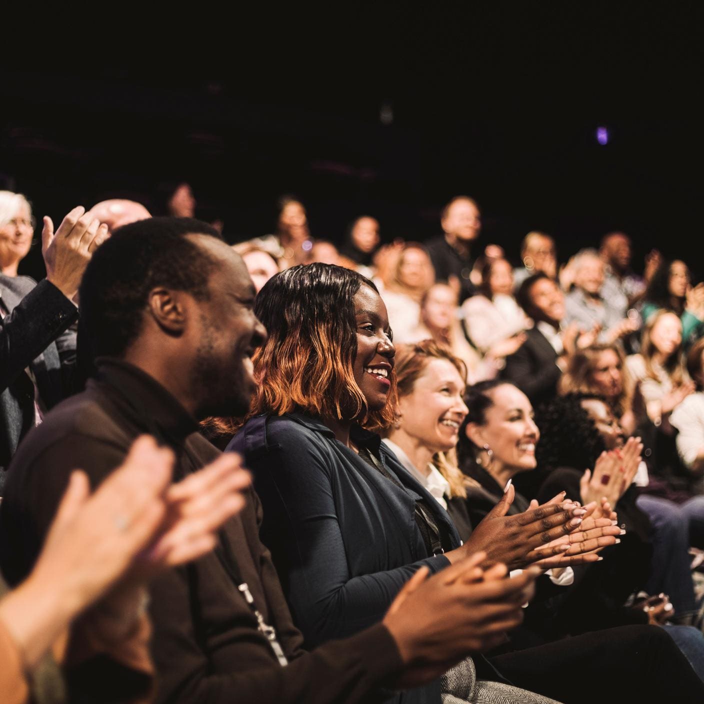 Smiling crowd applauding during a conference event