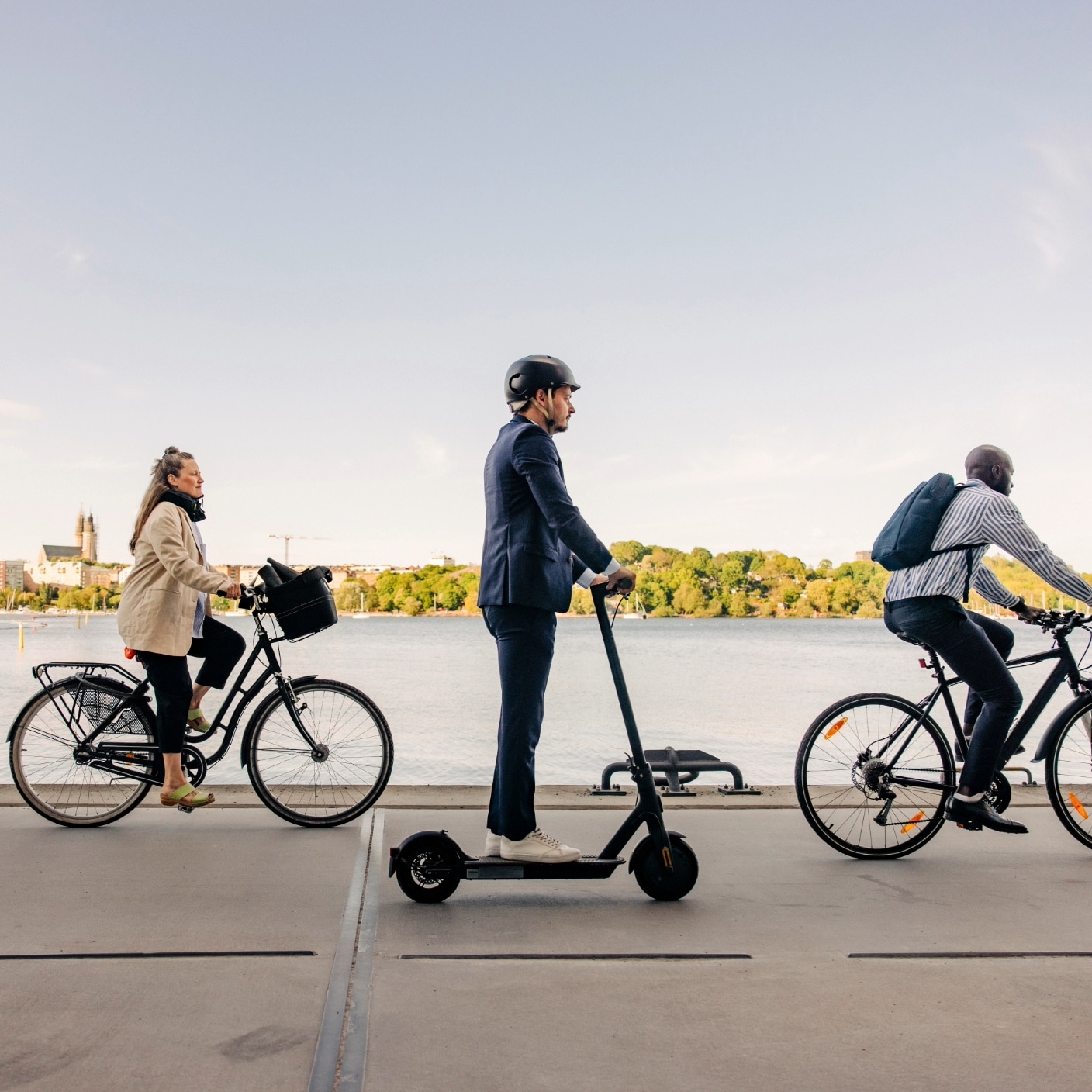 Male and business people commuting through cycles and electric push scooter on promenade