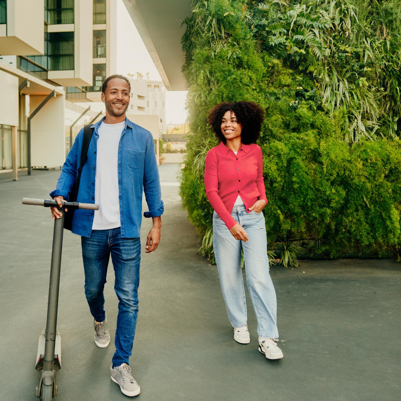 A couple smiling walking in a green city area