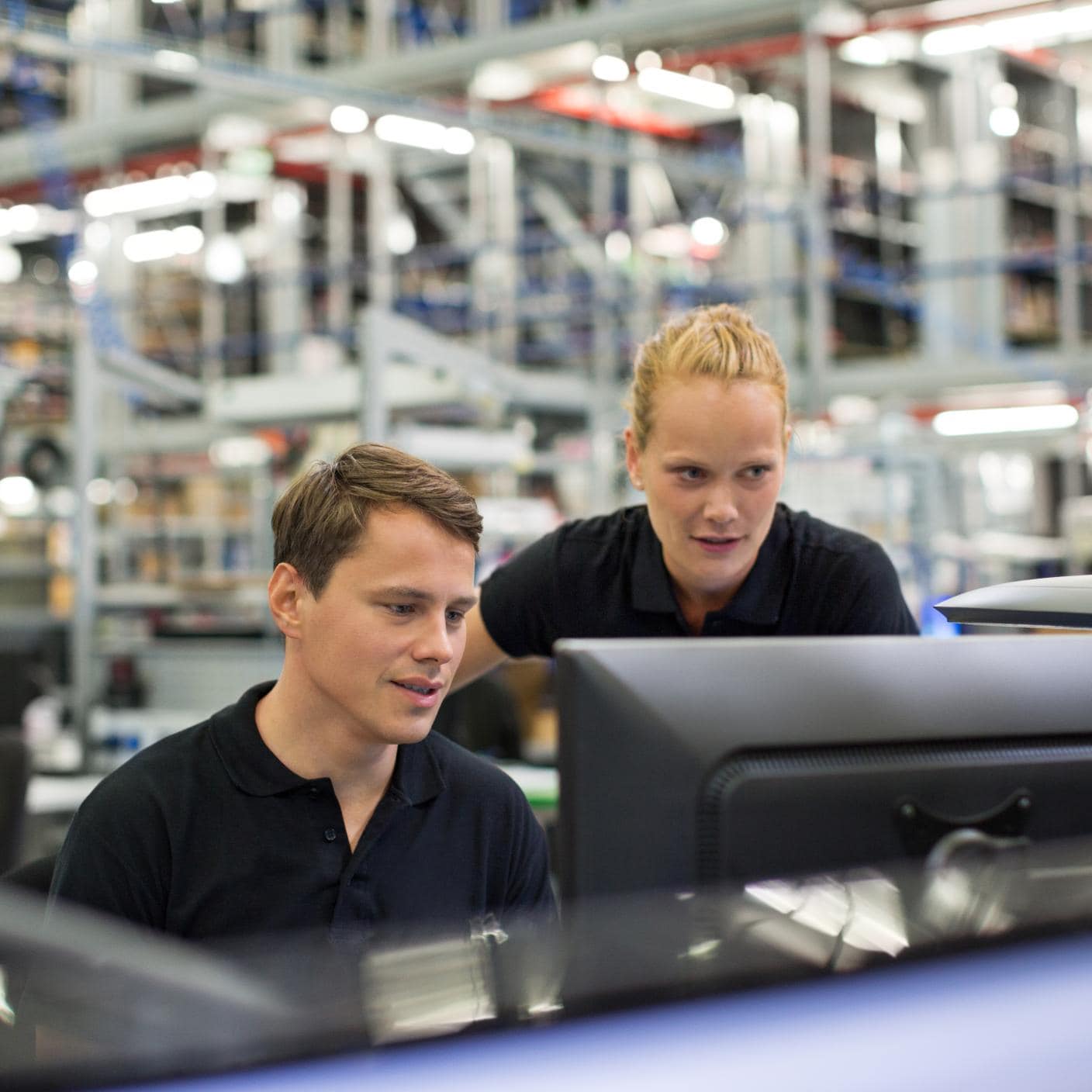 Employees using computer in logistics warehouse.