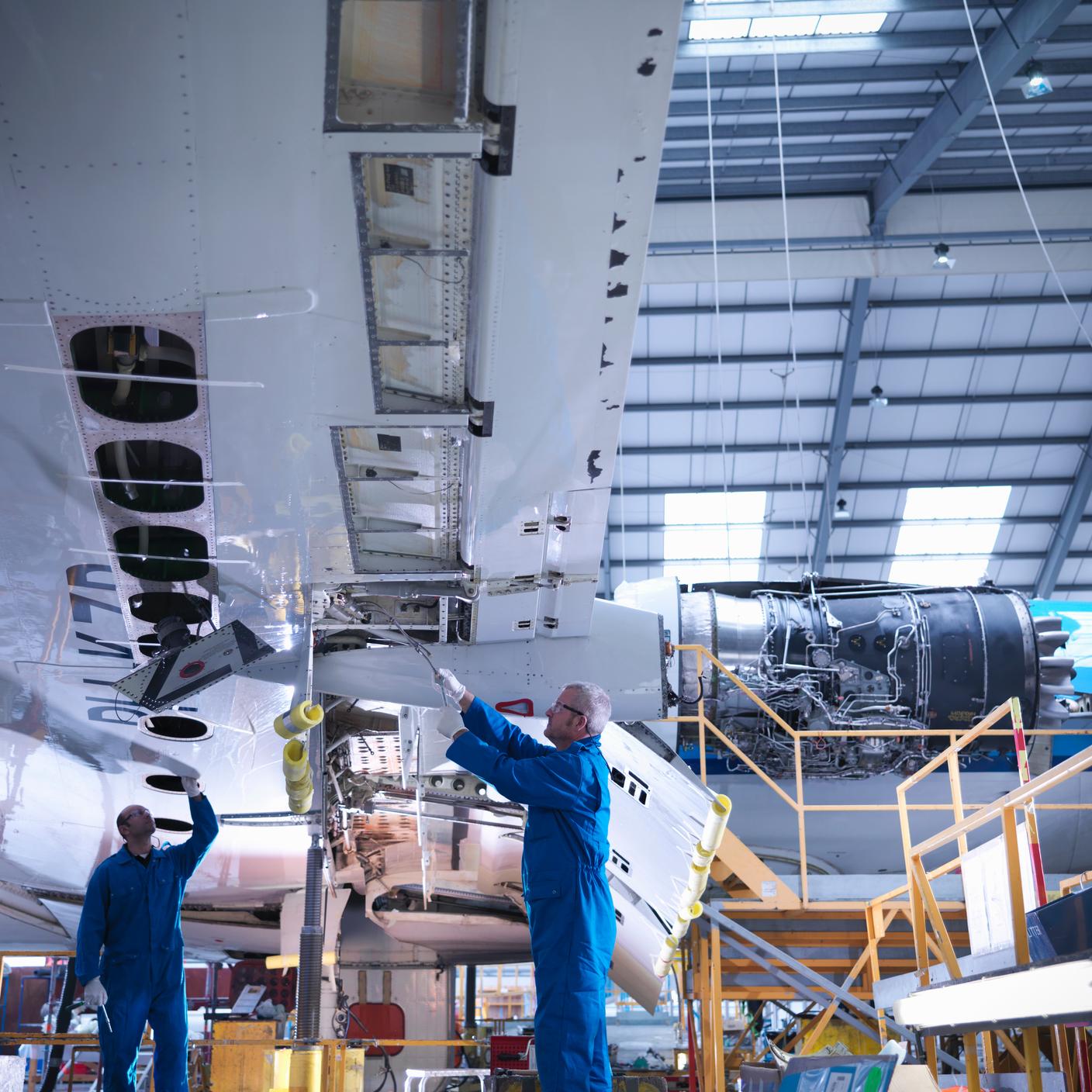 Aircraft engineers working on underside of wing of 737 jet plane