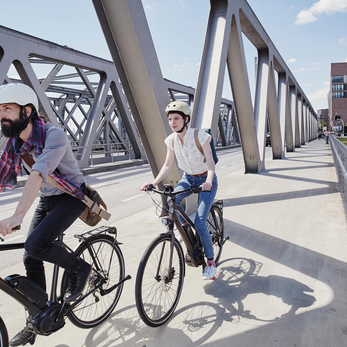 Two young person cycling on a bridge