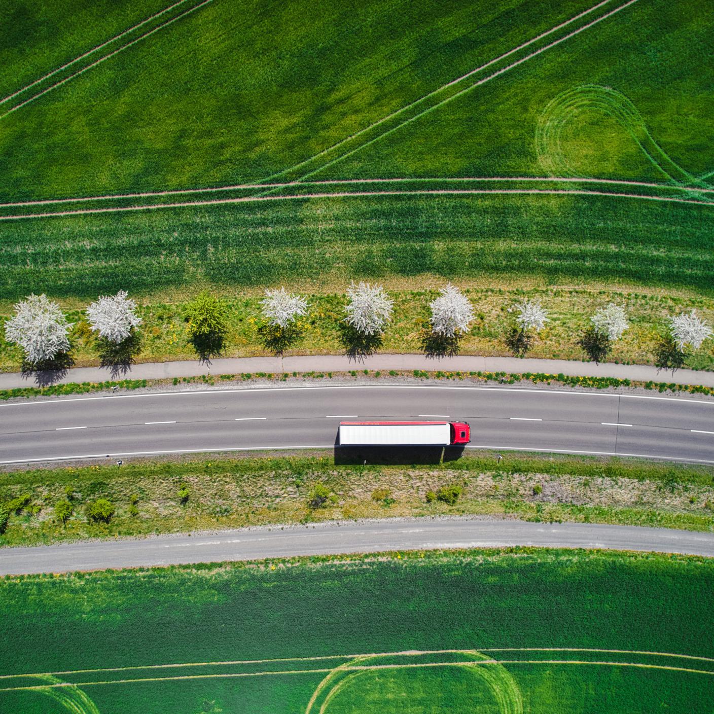 Drone shot direct above a truck moves along a single road.