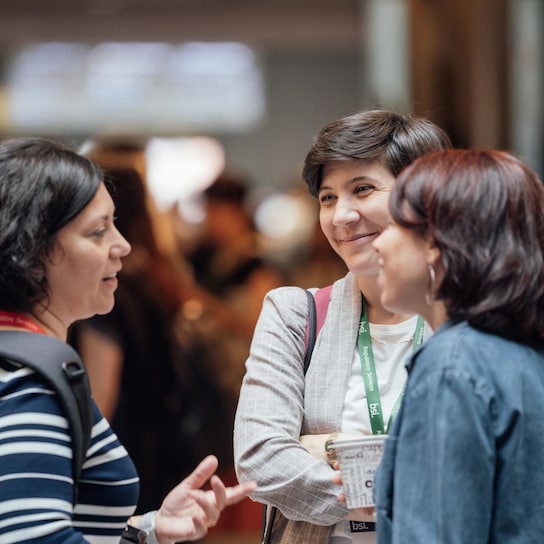 three women talking and smiling at event