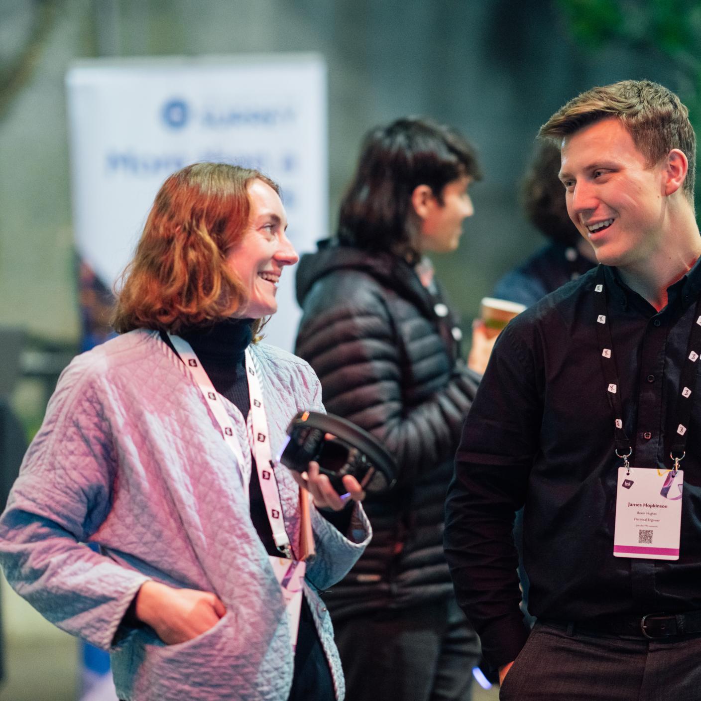 Two young professionals at a networking event chatting and smiling