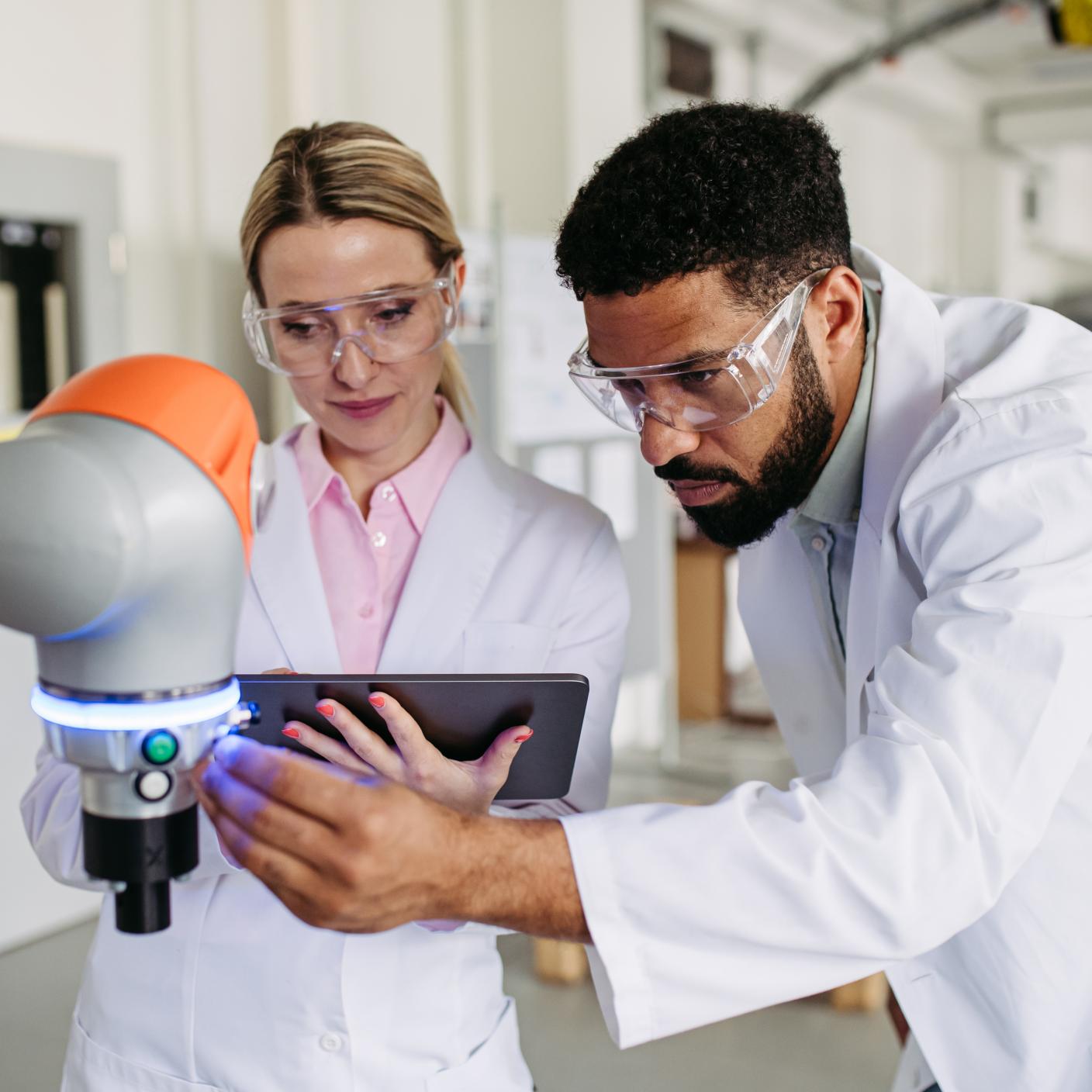 Robotic engineer colleagues working on robotic knee replacement surgery project, adjusting robots settings. Concept of robotics, engineering and computer science in healthcare.