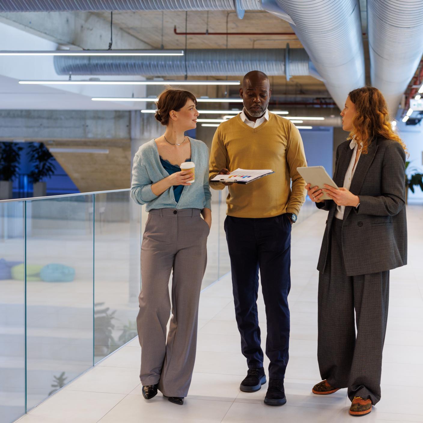 Business colleagues discussing project while walking in modern office. Diverse business people communicating and collaborating in a contemporary workplace