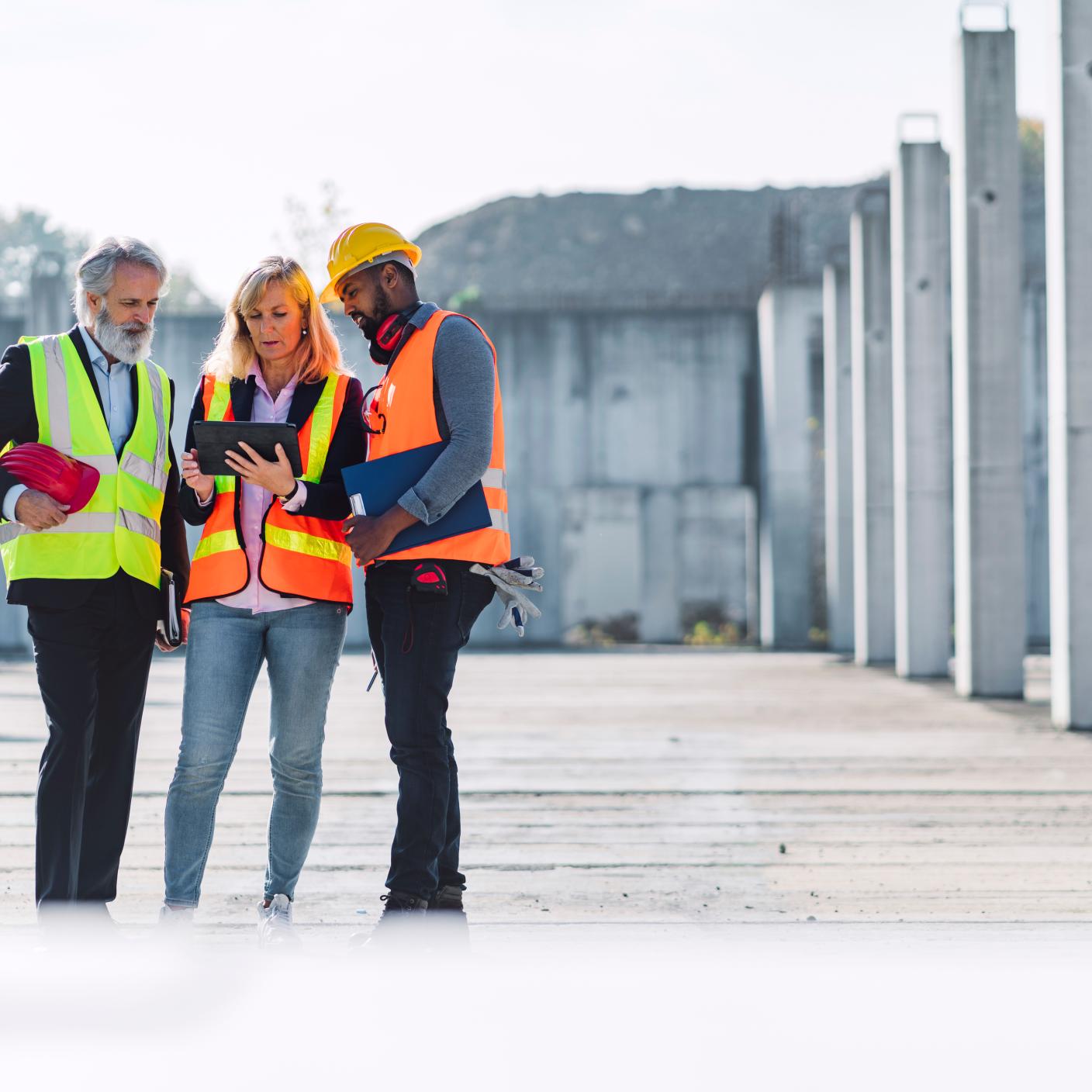 thee diverse people in reflective vests working on construction site