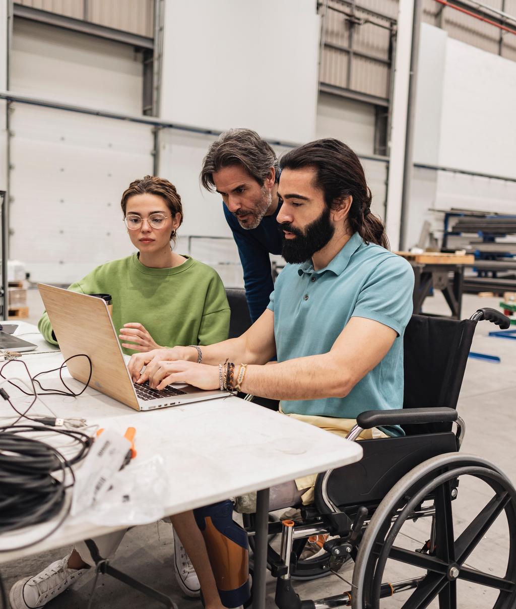 Engineer sitting in wheelchair working with colleagues in factory