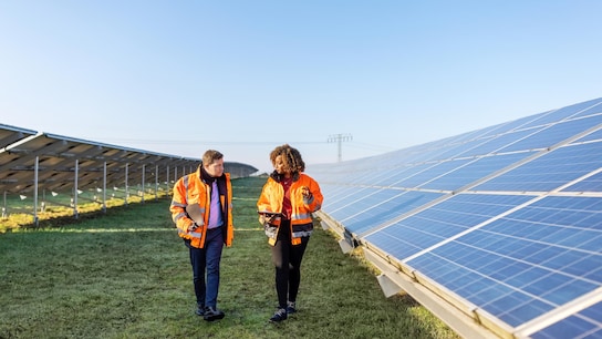 Male and female engineers working at solar power plant.