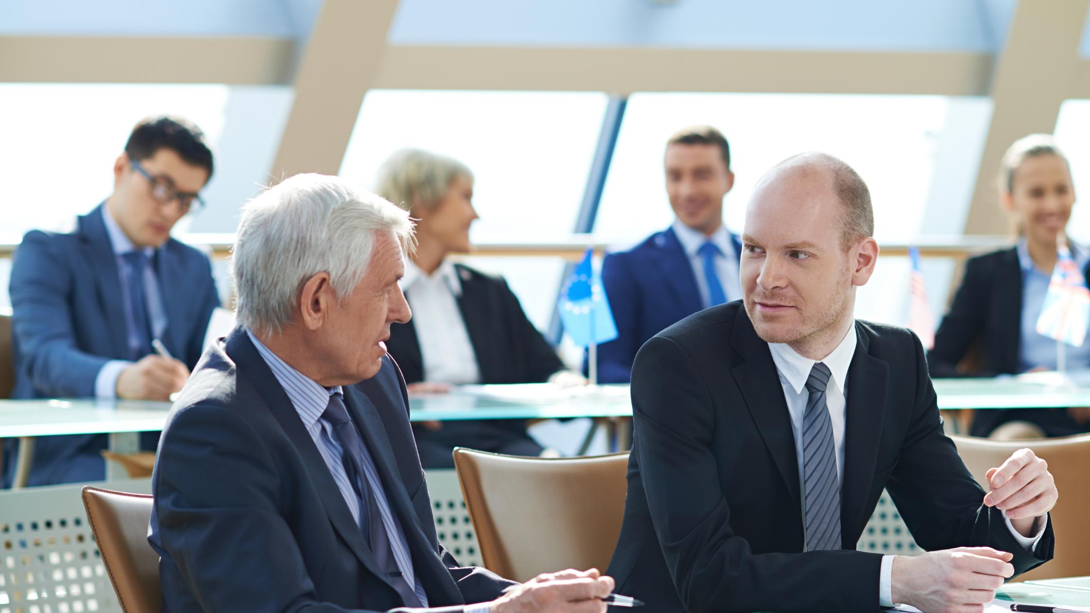 Two business people using a laptop together while sitting in a meeting