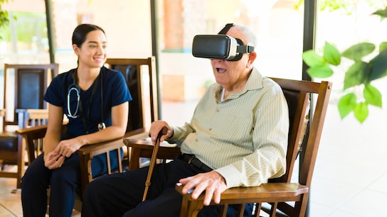 Immersive Erlebnisse – Ein aufgeregter alter Mann in den 80ern sieht glücklich aus und hat Spaß in der Kindertagesstätte, während er mit einer Virtual Reality-Brille spielt