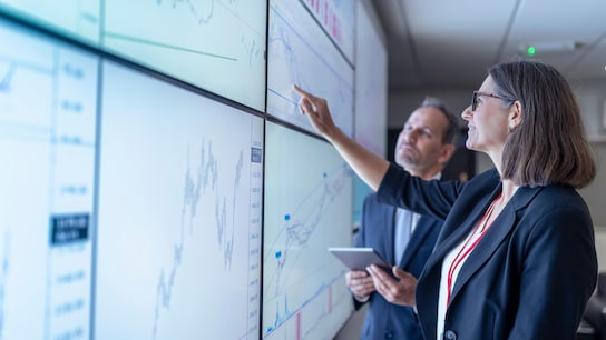 Two people discussing by wall screens.