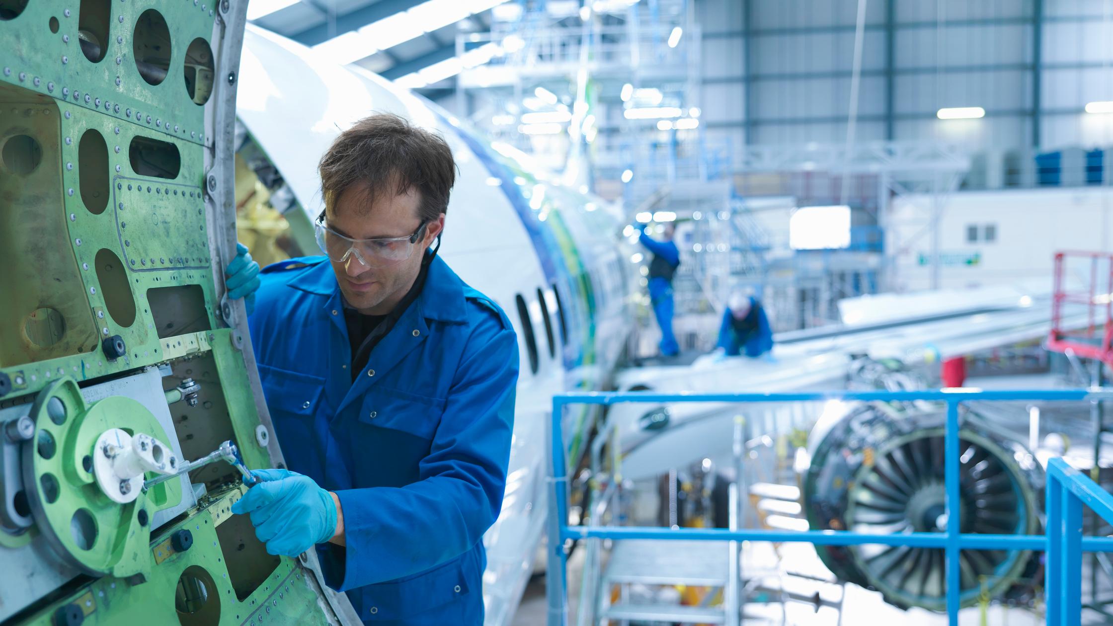 Future flight landscape - Engineer working on aircraft door in aircraft maintenance factory