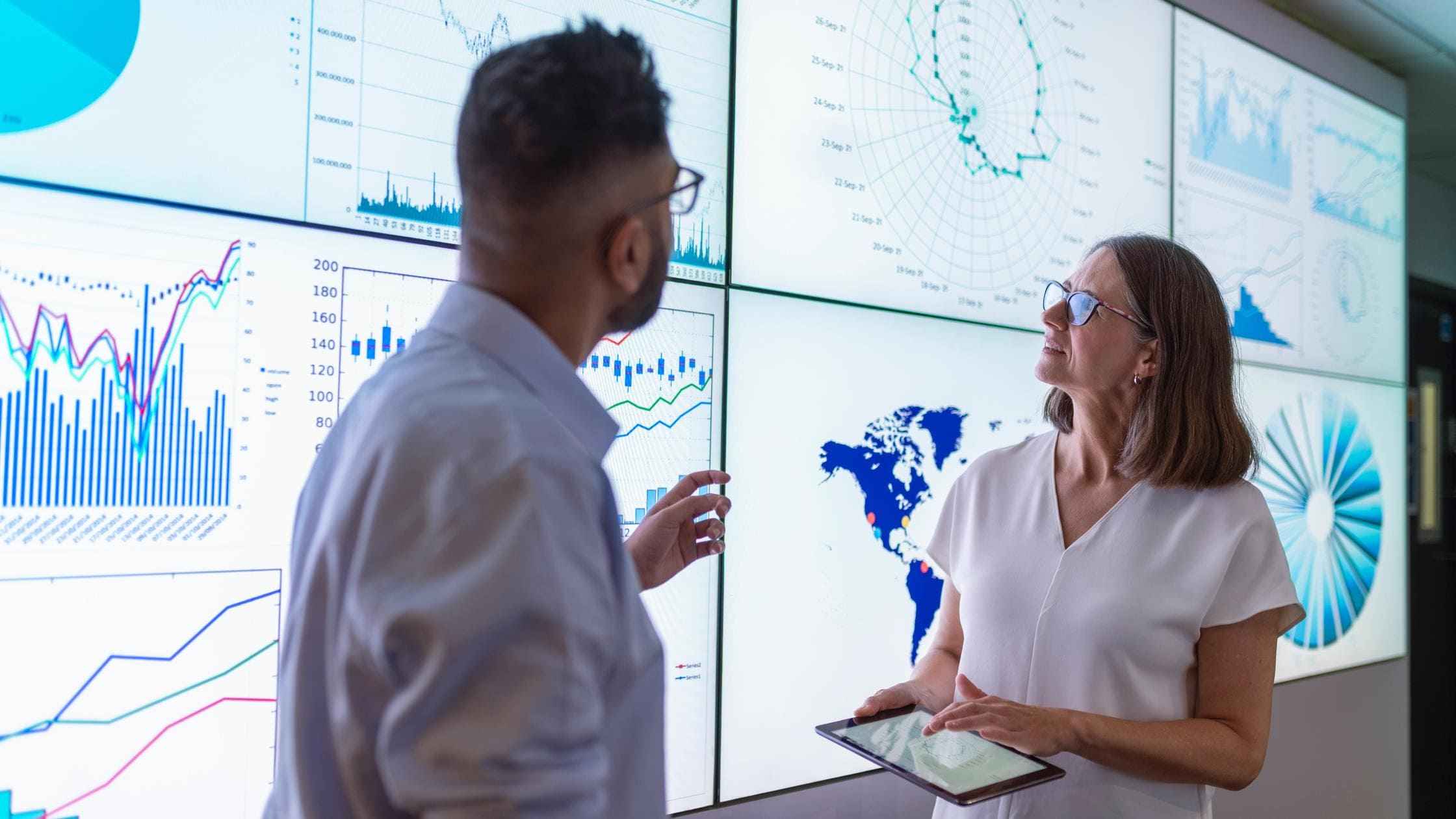 Man and woman reviewing large data screens