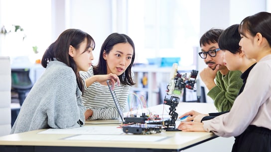 Employees around a table consulting their screen and discussing